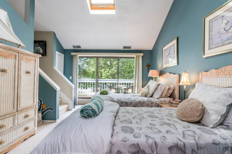 a bedtoom with two single beds and glass doors to a balcony