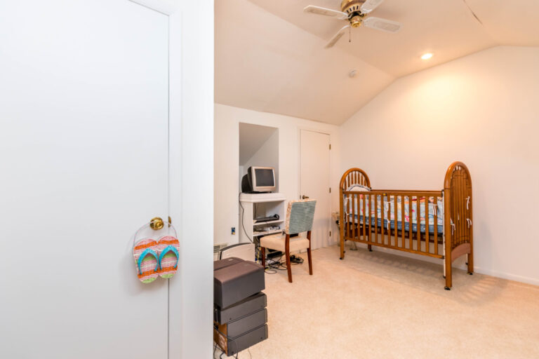 a cozy room with a crib, a striped couch, and bookshelf