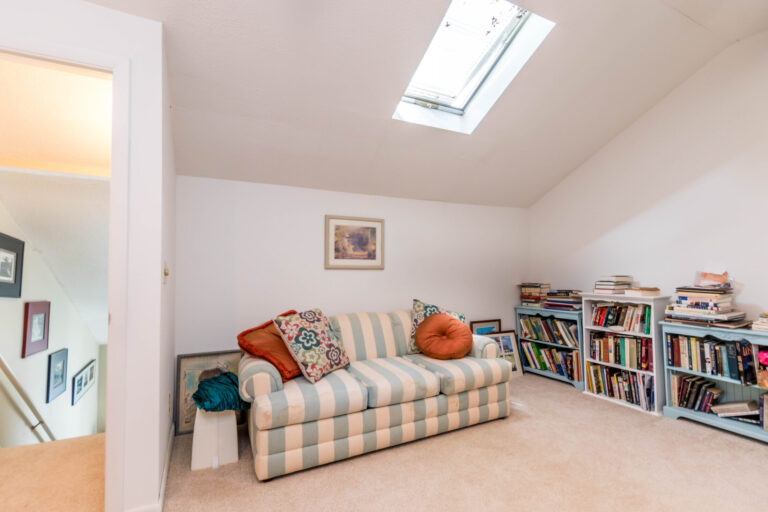 a cozy room with a crib, a striped couch, and bookshelf