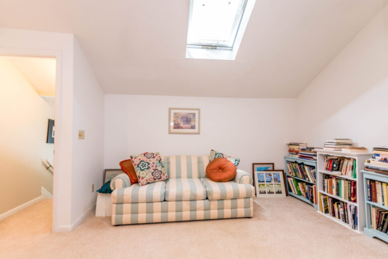 a cozy room with a crib, a striped couch, and bookshelf