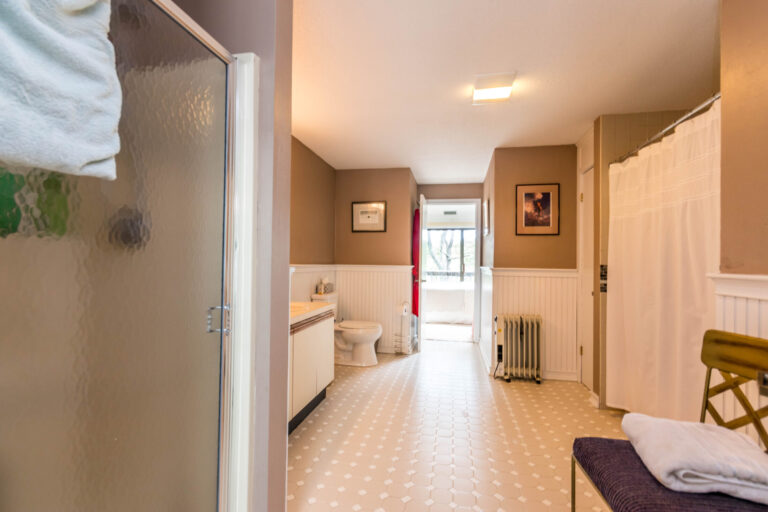 Spacious bathroom with a shower, toilet, vanity, and a view through the window.