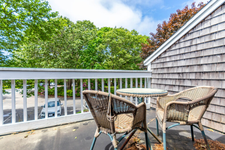 a balcony with 2 chairs and a rounded table