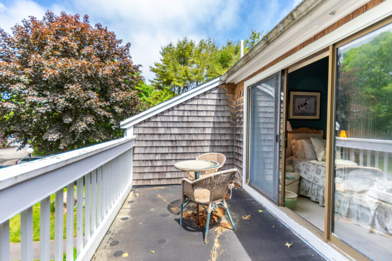 a balcony with 2 chairs and a rounded table