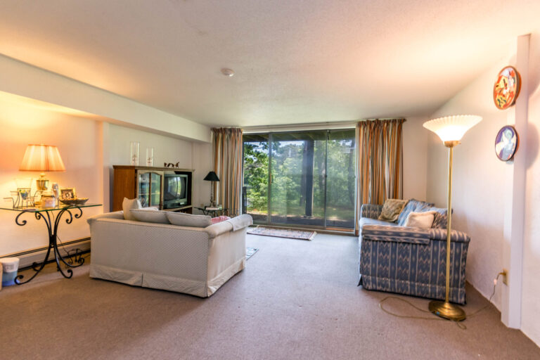 a family room with a simple couch, a vintage-style TV, and a small wooden cabinet
