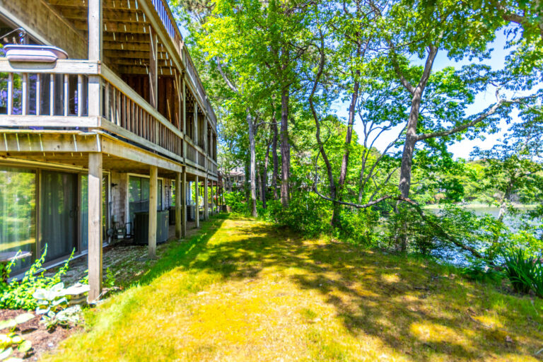 backyard view of 5 Riverview Ave Unit C, Mashpee, MA 02649 surrounded by trees and access to water