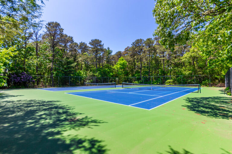 an open tennis court surrounded by tall trees