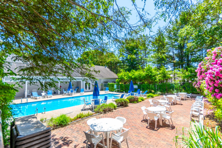 a swimming pool with white round tables and chairs on the side