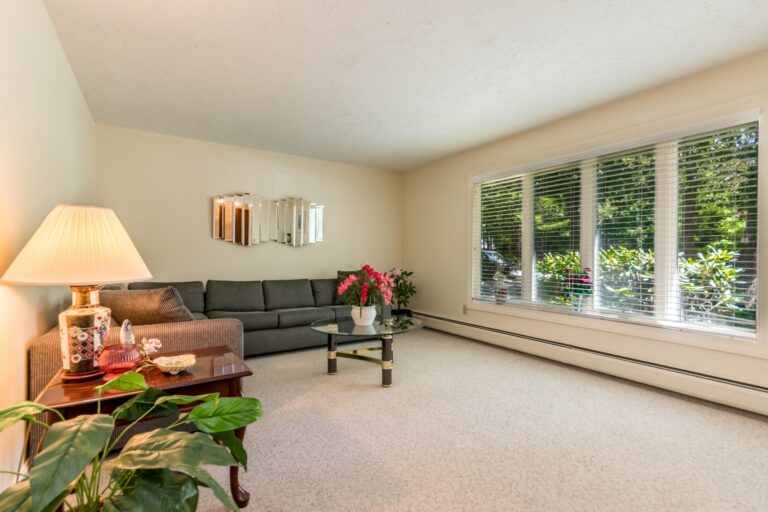 a spacious living room with an L shape couch, tables and plants