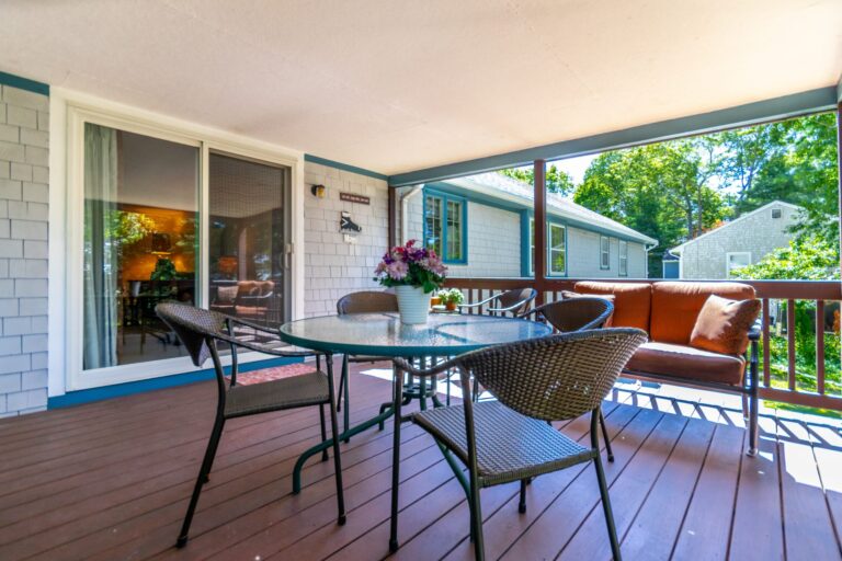 a covered deck with metal furnitures and a glass door entrance to the property