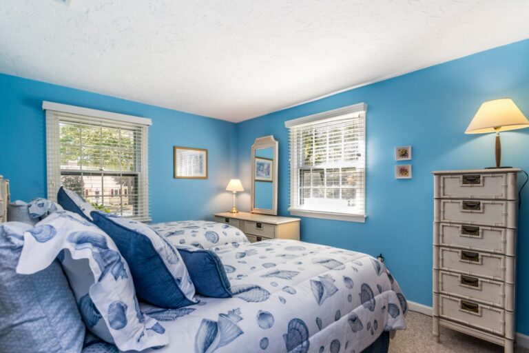 a blue painted bedroom with 2 beds and wooden furnitures