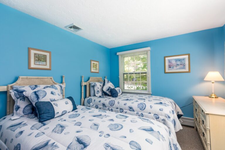 a blue painted bedroom with 2 beds and wooden furnitures