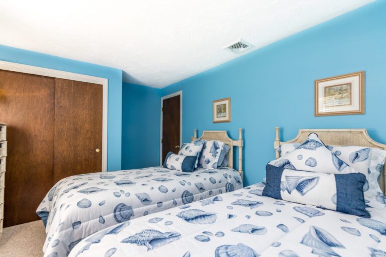 a blue painted bedroom with 2 beds and wooden furnitures