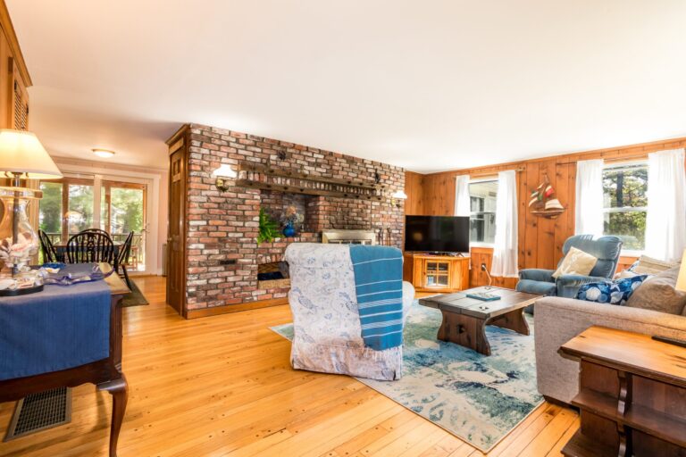 a living room with couch, fireplace, table and TV