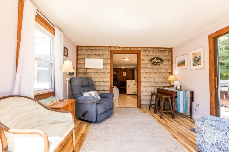 a sun room with couch, books and huge glass window pane