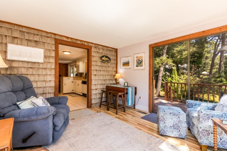 a sun room with couch, books and huge glass window pane