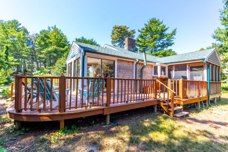 a wooden deck of a house surrounded by trees during daytime