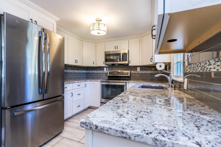 a kitchen with granite countertops, stainless steel appliances and white cabinets