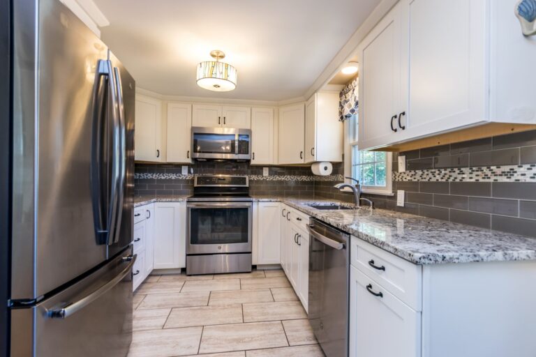 a kitchen with granite countertops, stainless steel appliances and white cabinets