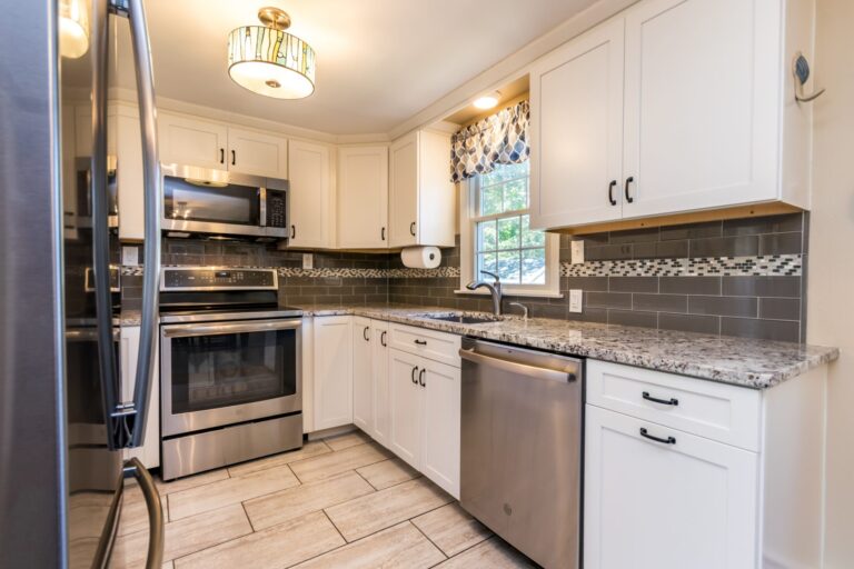 a kitchen with granite countertops, stainless steel appliances and white cabinets