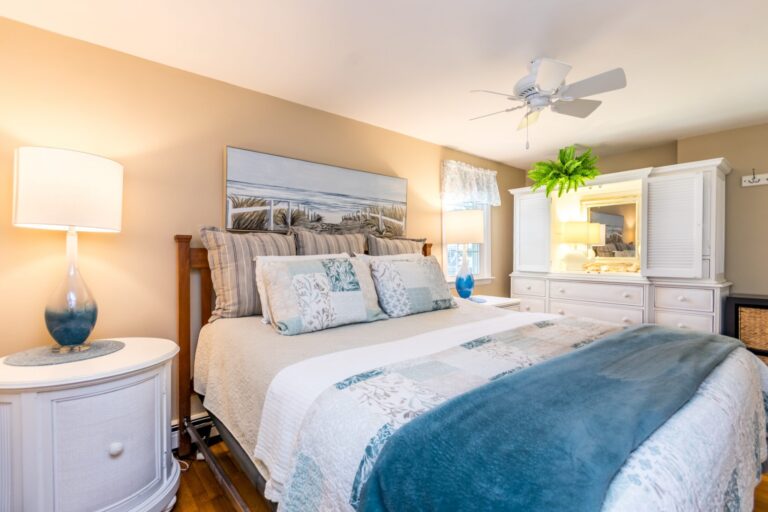 a bedroom with a bed with blue blanket and white dresser
