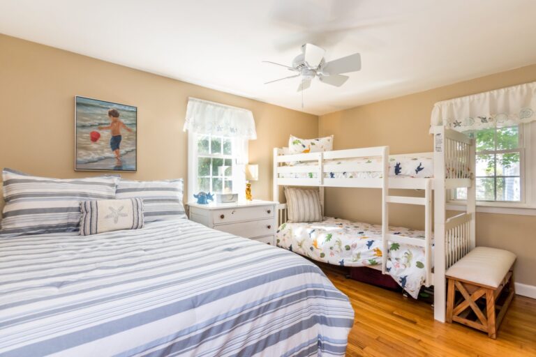 a oom with bunk beds and a regular sized bed with white dresser