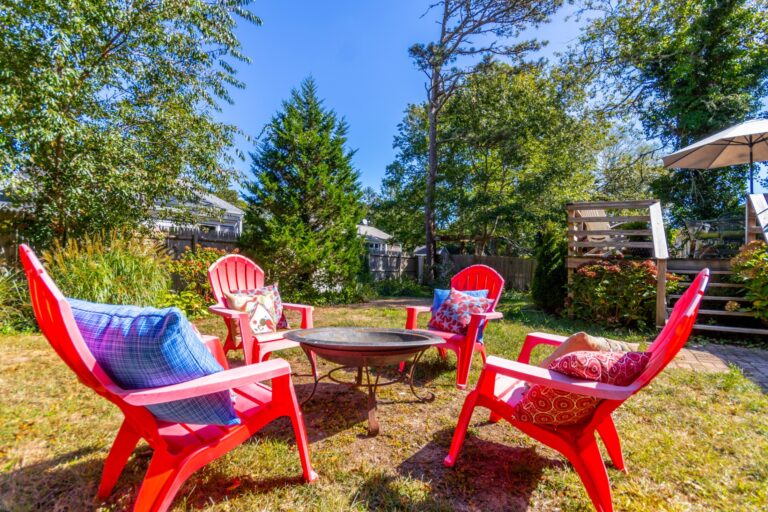 four red plastic chairs in the middle of a backyard