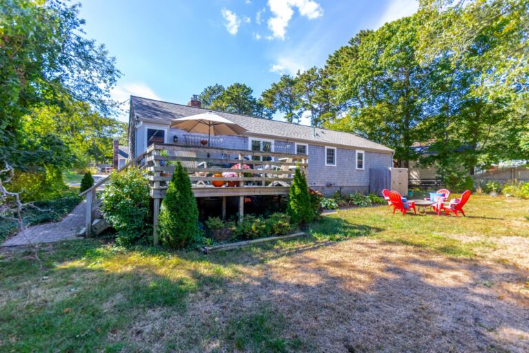 four red plastic chairs in the middle of a backyard