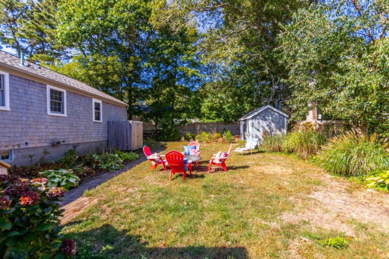 four red plastic chairs in the middle of a backyard