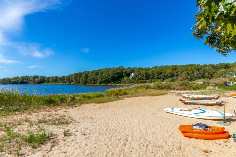 front view of a lake with kayaks on the sand
