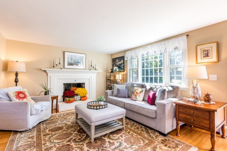 a living room with fireplace, wooden furnitures and lots of natural light
