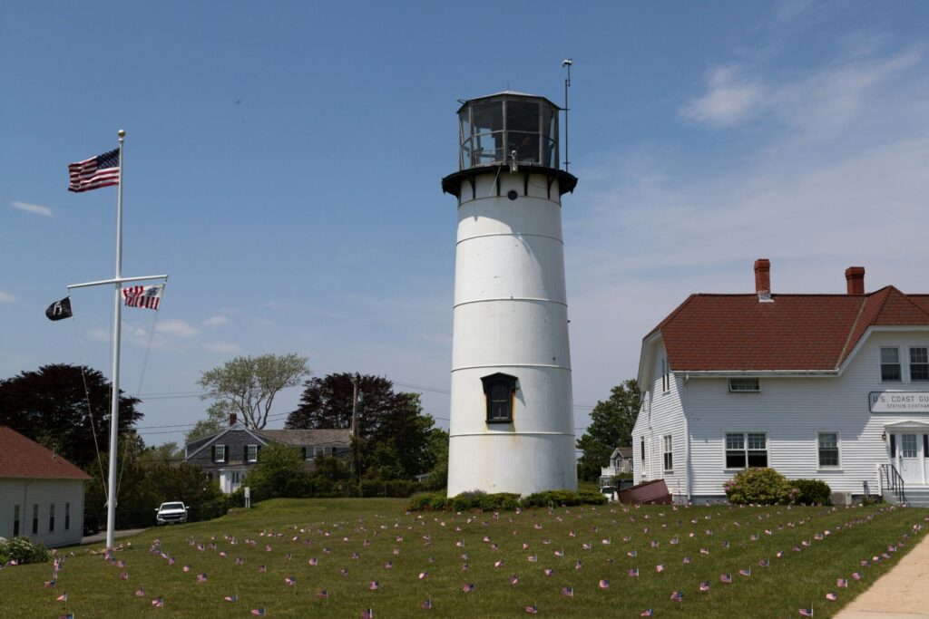 a lighthouse with a flag with sand point light in the background