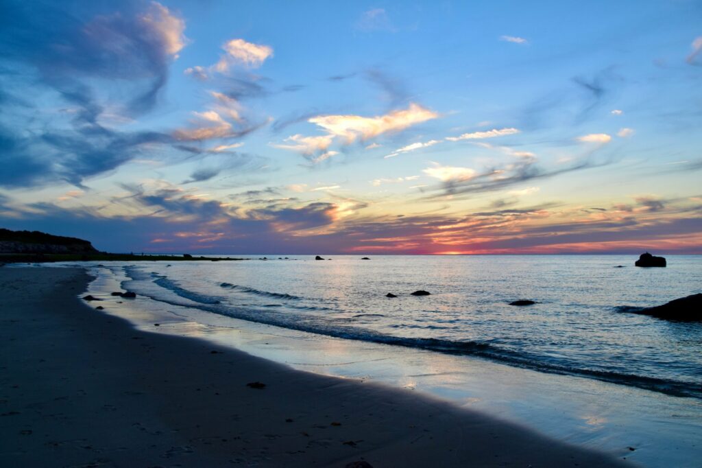 the sun is setting over the water at the beach