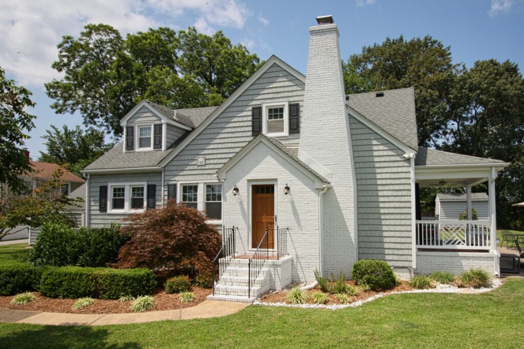 a gray house with a white porch and a brown door