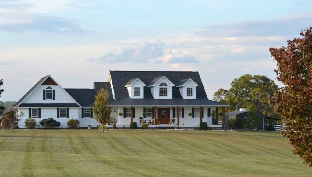 a large white farmhouse with warp around porch