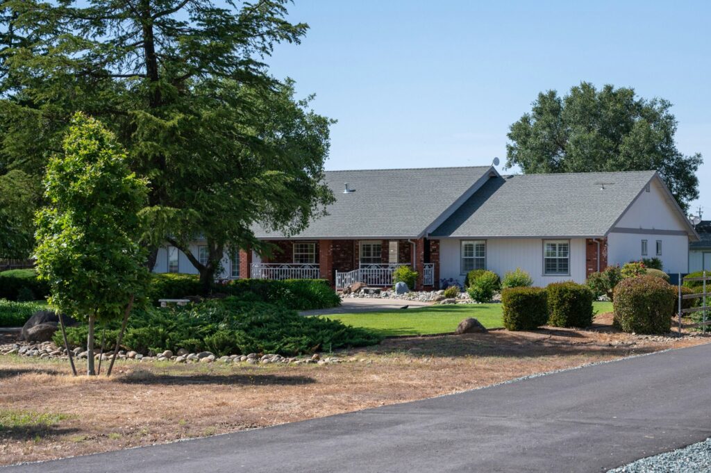 a house with large lawn and trees in front