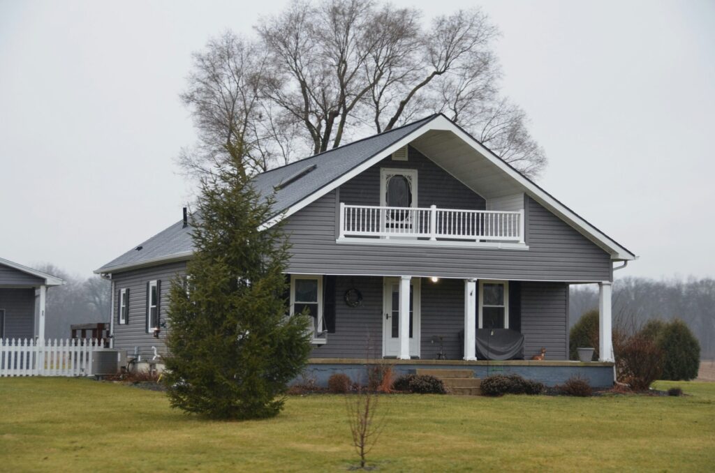 a gray house with a white porch and white fence