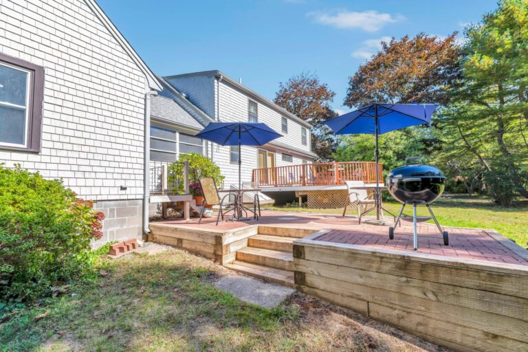 a landscaped backyard featuring a multi-level wooden deck with brick paver inlays
