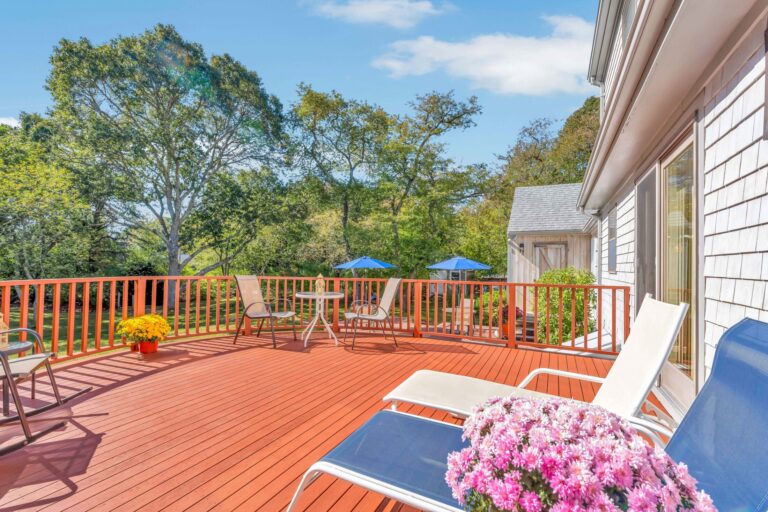 a deck with chairs and surrounded by mature trees