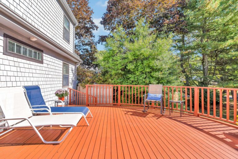 well-maintained rear deck featuring modern lounge chairs and surrounded by mature trees