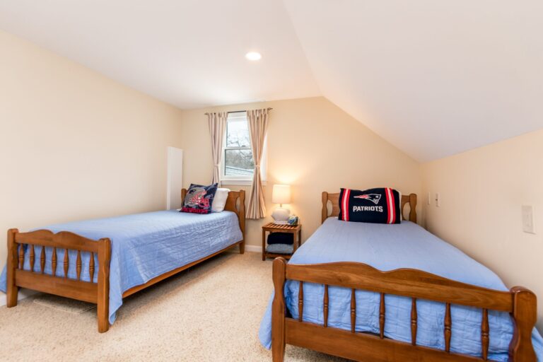 a bedroom featuring two twin beds with wooden frames and light blue bedding