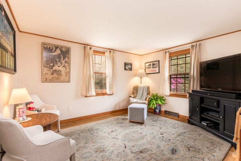 a den with chairs, television and small windows
