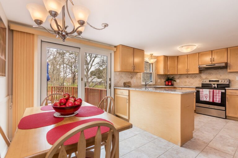 a cozy kitchen and dining area featuring maple-toned cabinets, a granite countertop island, and a sliding glass door leading to an outdoor deck