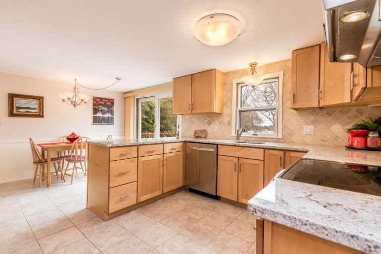 a cozy kitchen and dining area featuring maple-toned cabinets, a granite countertop island, and a sliding glass door leading to an outdoor deck