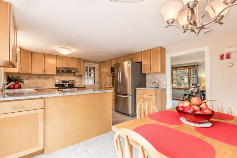 a cozy kitchen and dining area featuring maple-toned cabinets, a granite countertop island