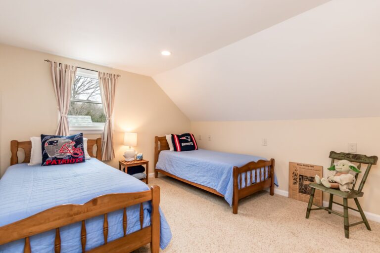 a bedroom featuring two twin beds with wooden frames and light blue bedding